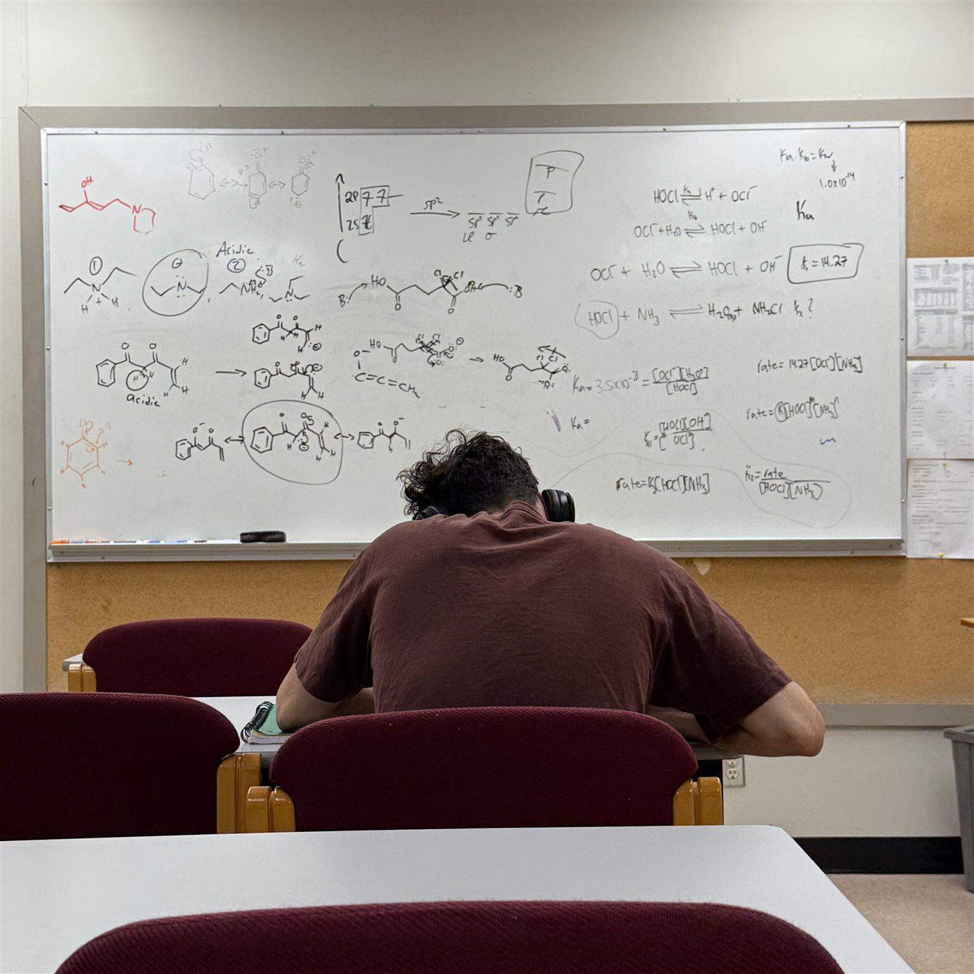 A student working through chemistry problems on a whiteboard