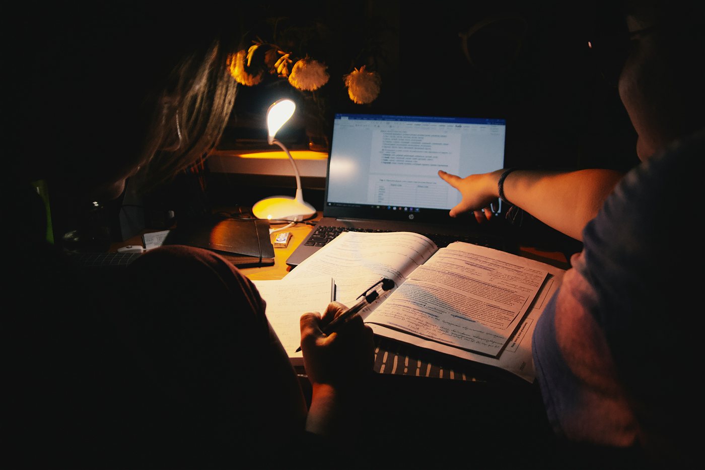 A student studying at a desk with a laptop in the evening