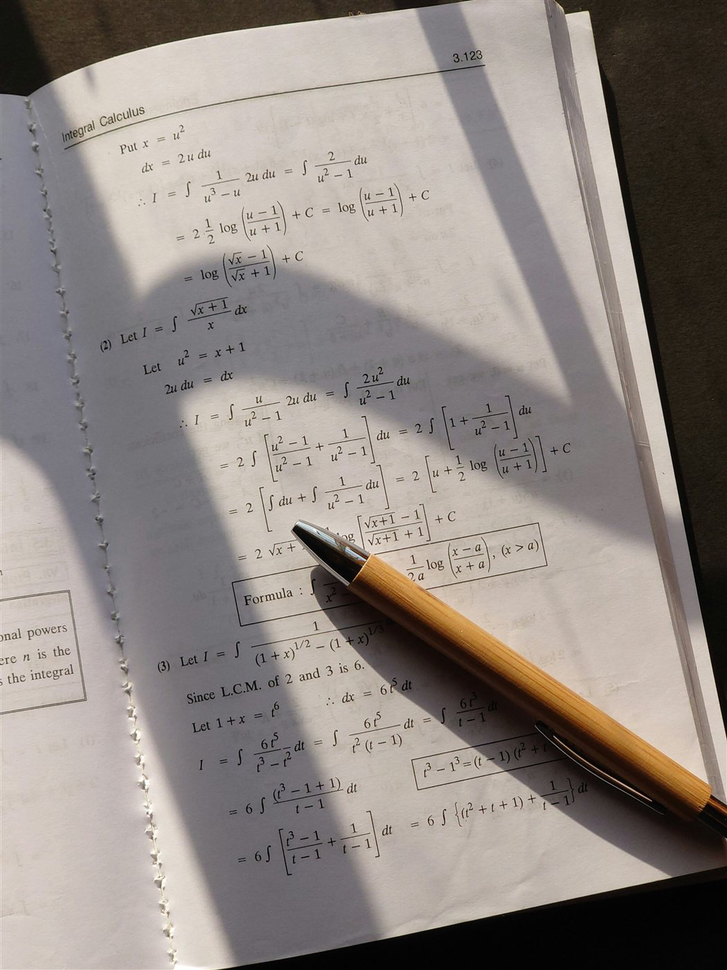 An open calculus textbook with a pen