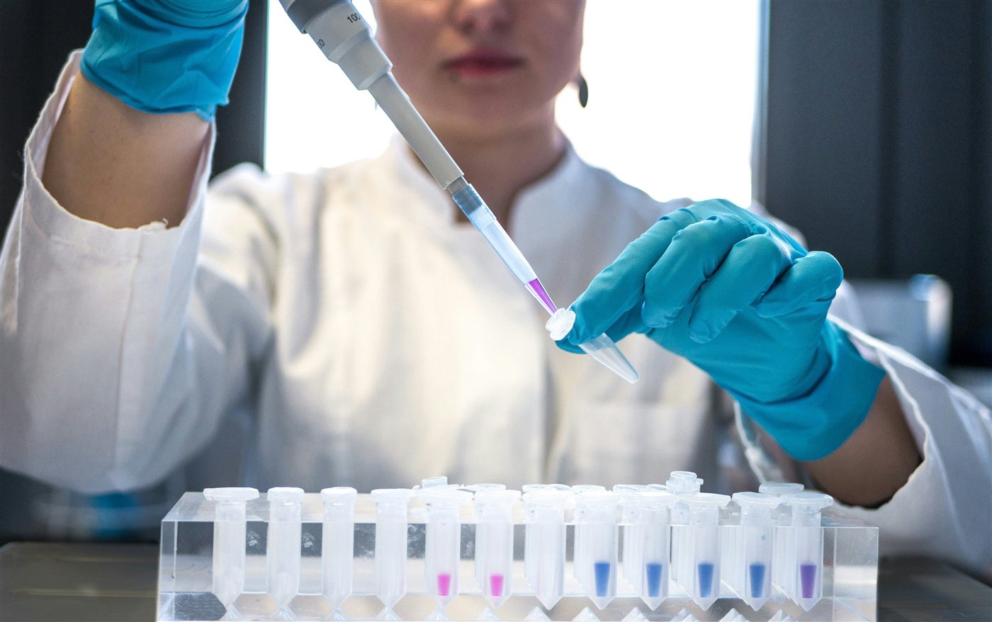 A student using a pipette with test tubes in a chemistry lab