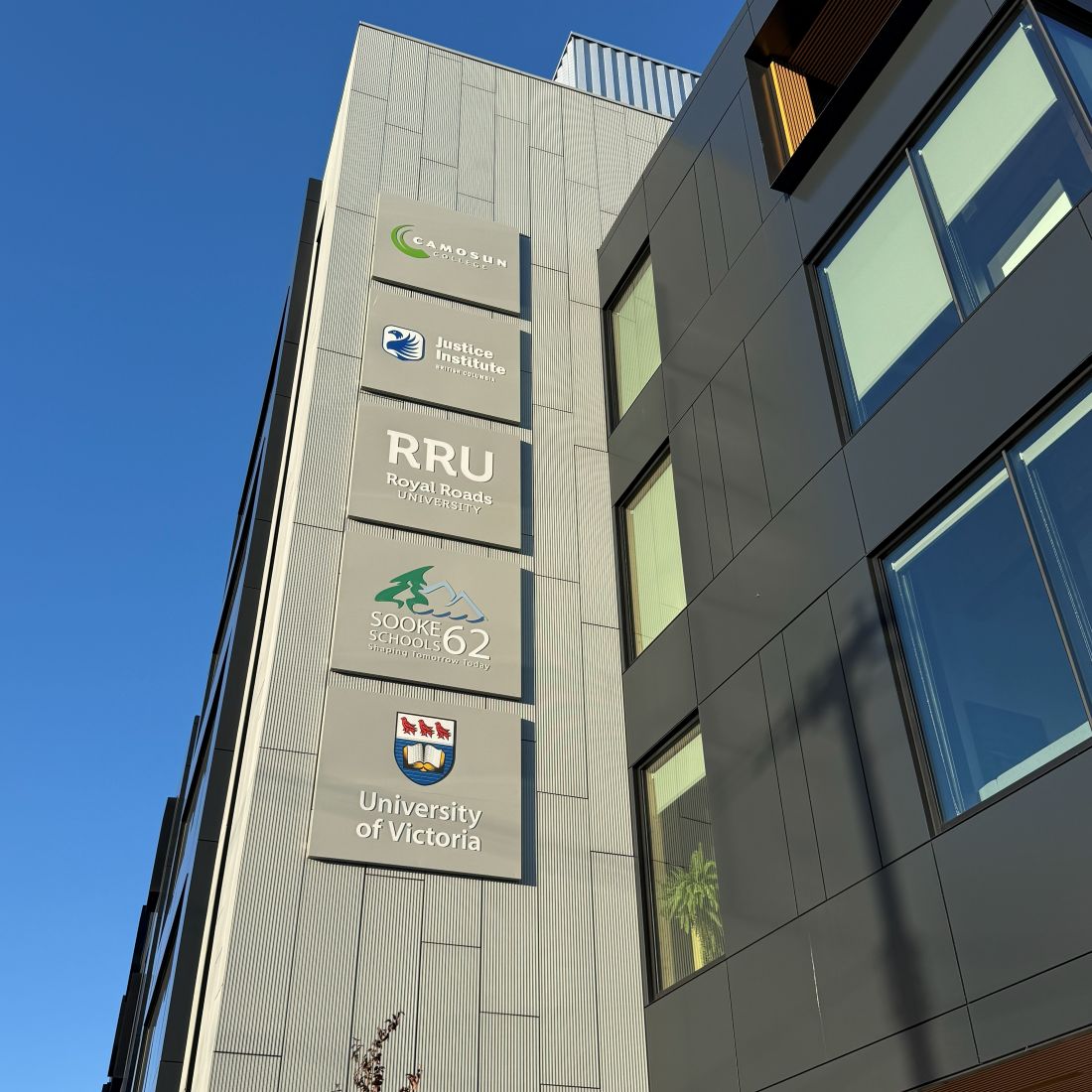 The John Horgan Campus on Goldstream Avenue in Langford, with building signage for Camosun College, the Justice Institute of British Columbia, Royal Roads University, Sooke School District 62, and the University of Victoria.