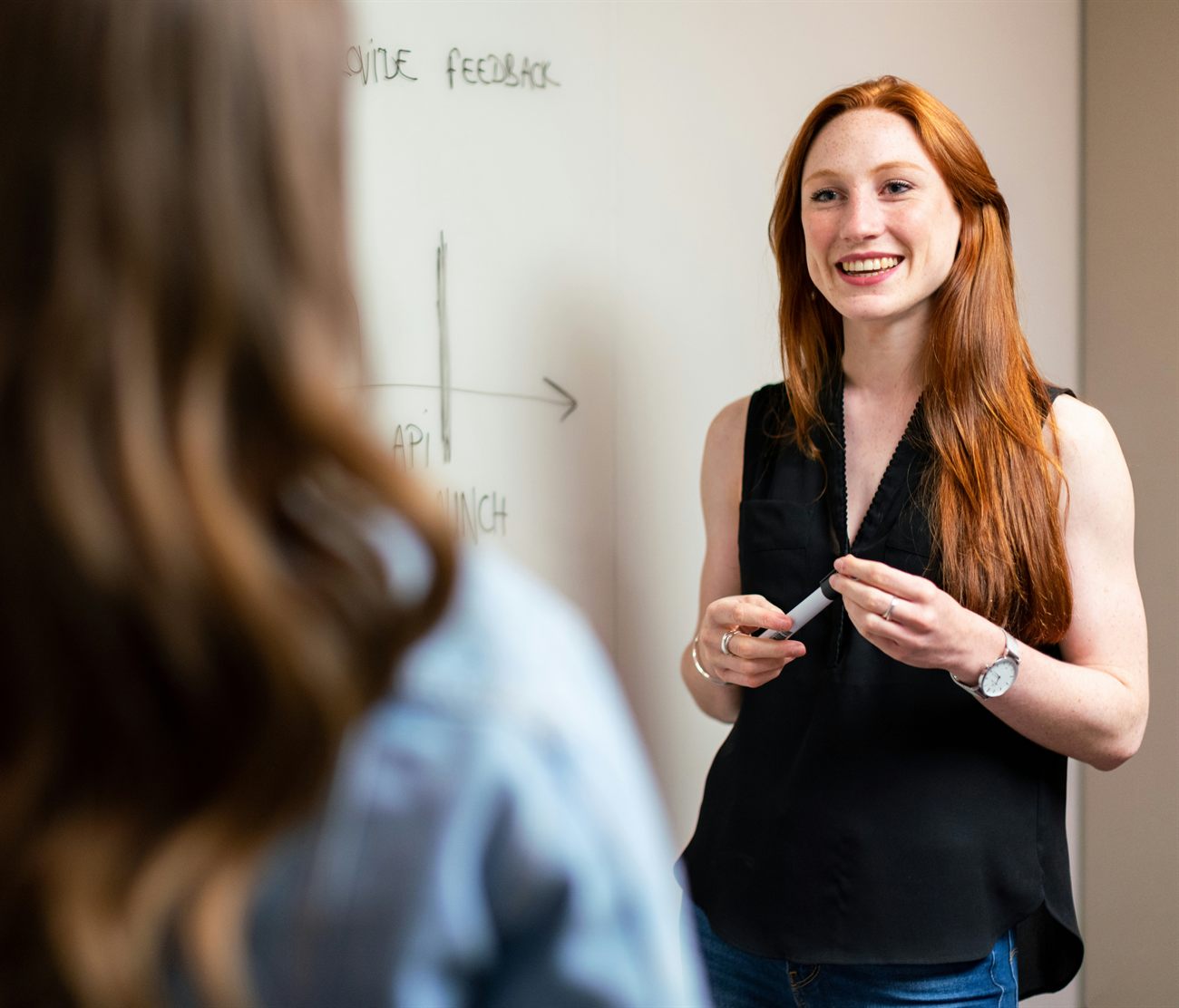 A tutor explaining a concept at a whiteboard to a high school student